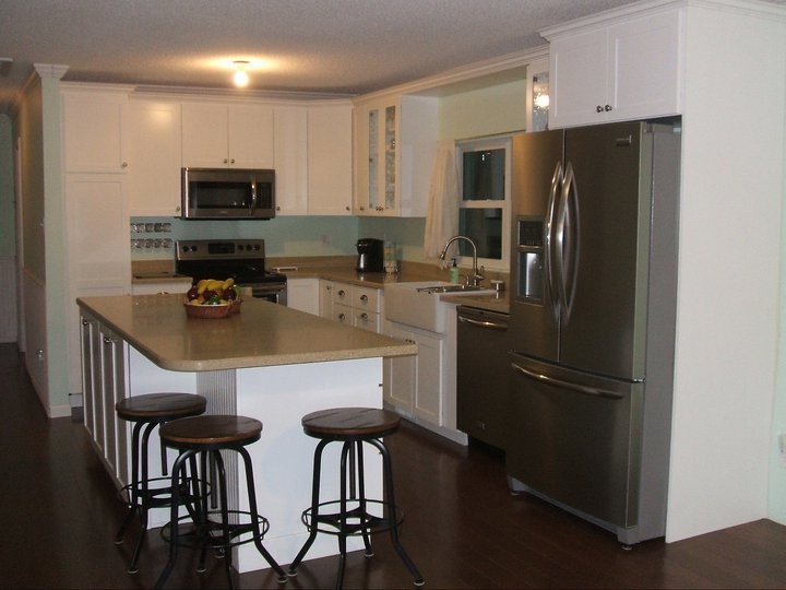 Photo of a mid-sized country u-shaped kitchen pantry in Tampa with a farmhouse sink, shaker cabinets, white cabinets, solid surface benchtops, stainless steel appliances, beige splashback, dark hardwood floors and multiple islands.