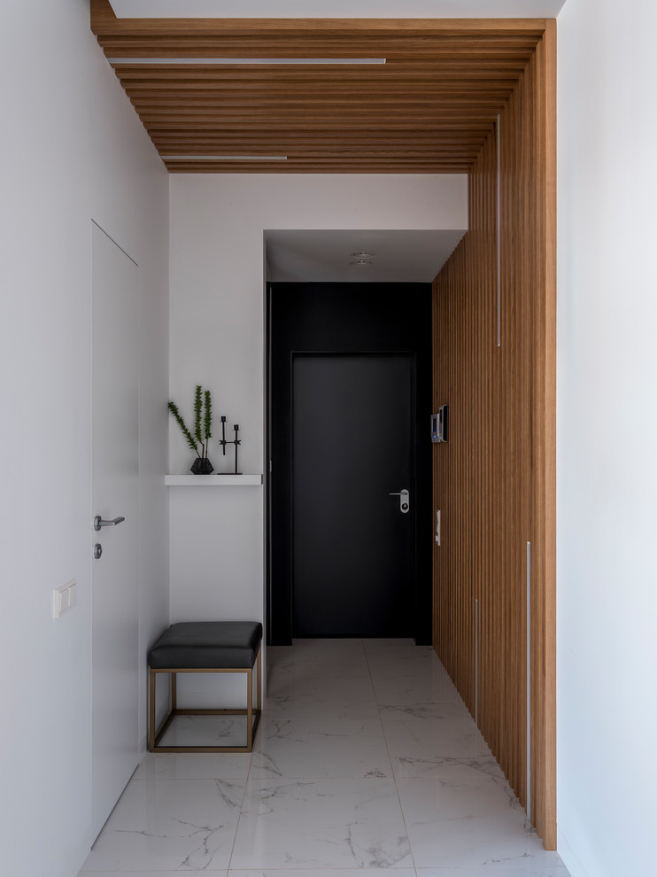 This is an example of a contemporary front door in Moscow with white walls, a single front door, a black front door and white floor.