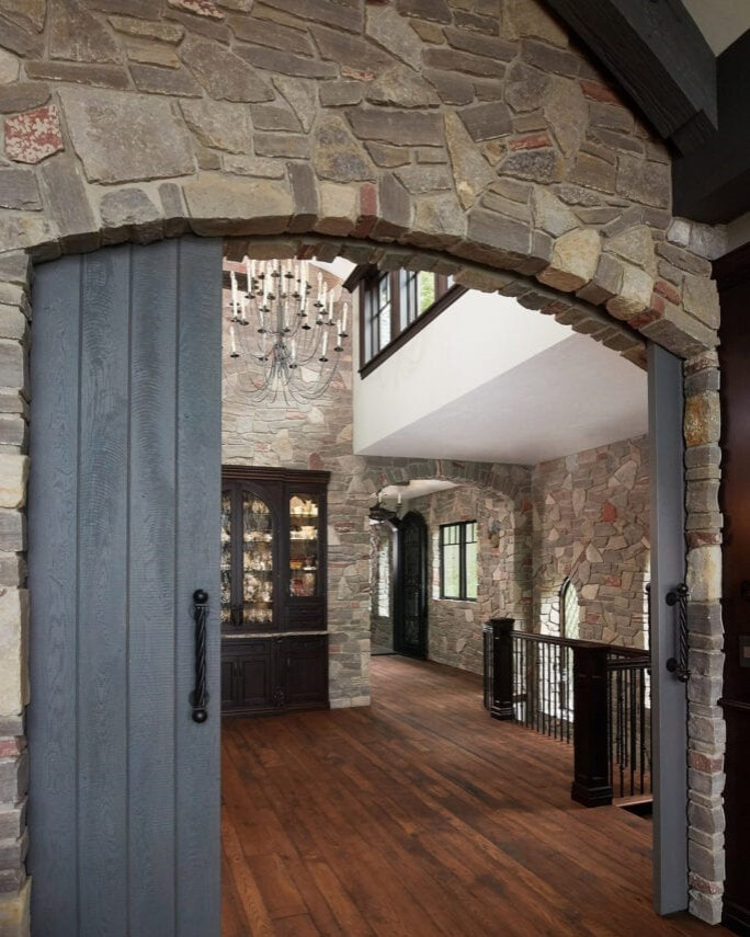 他の地域にあるラグジュアリーな広いトラディショナルスタイルのおしゃれな玄関ロビー (茶色い壁、濃色無垢フローリング、グレーのドア、茶色い床、三角天井) の写真