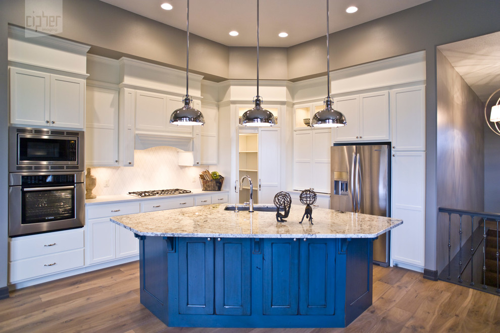 Example of a mid-sized transitional l-shaped medium tone wood floor and brown floor eat-in kitchen design with an undermount sink, raised-panel cabinets, white cabinets, granite countertops, white backsplash, porcelain backsplash, stainless steel appliances and an island