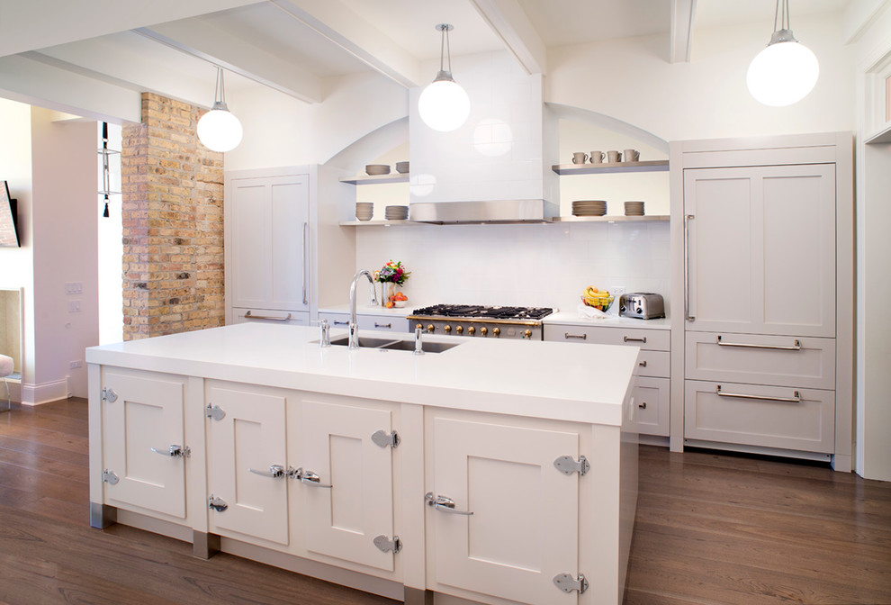 Example of a mid-sized transitional galley medium tone wood floor eat-in kitchen design in Chicago with a double-bowl sink, shaker cabinets, white cabinets, quartzite countertops, white backsplash, subway tile backsplash, paneled appliances and an island