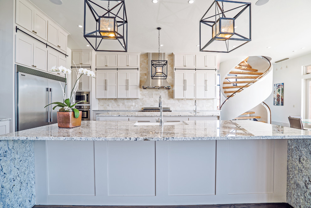 Expansive contemporary open plan kitchen in Oklahoma City with a farmhouse sink, flat-panel cabinets, white cabinets, granite benchtops, white splashback, mosaic tile splashback, stainless steel appliances, dark hardwood floors and multiple islands.