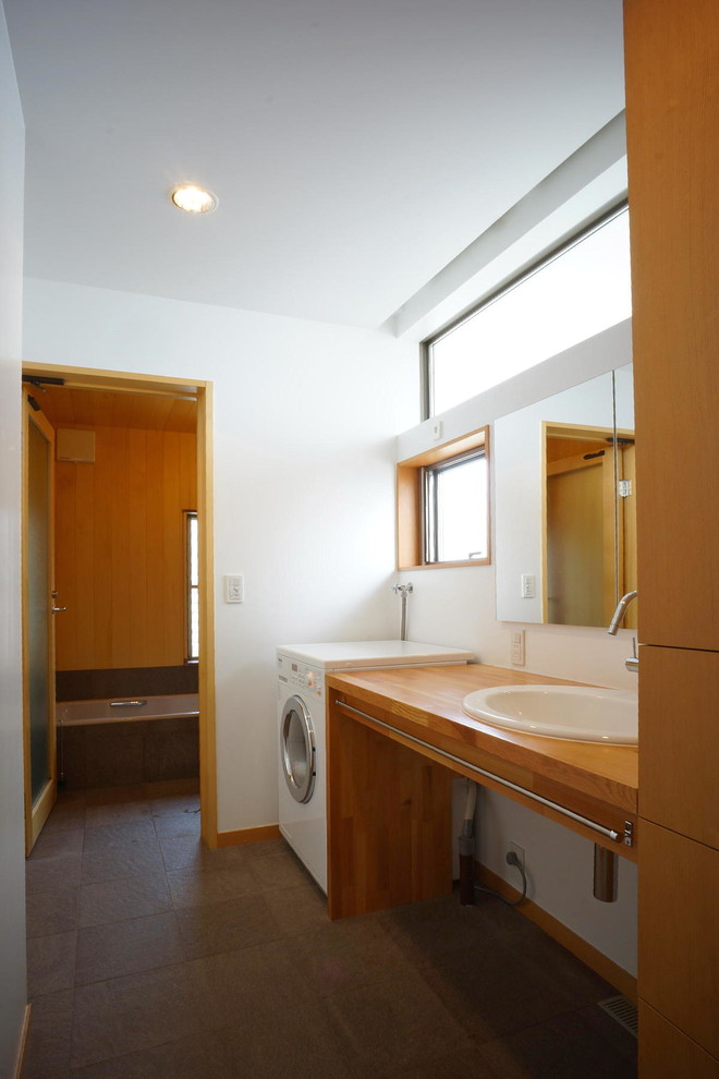Mid-sized modern powder room in Other with flat-panel cabinets, light wood cabinets, a one-piece toilet, white walls, porcelain floors, a drop-in sink, wood benchtops and brown floor.