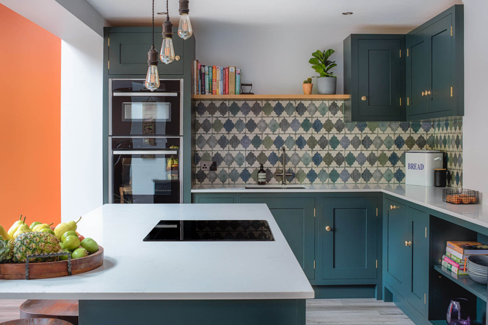 This is an example of a mid-sized contemporary l-shaped eat-in kitchen in Other with a drop-in sink, shaker cabinets, green cabinets, quartzite benchtops, green splashback, ceramic splashback, laminate floors, with island and white benchtop.