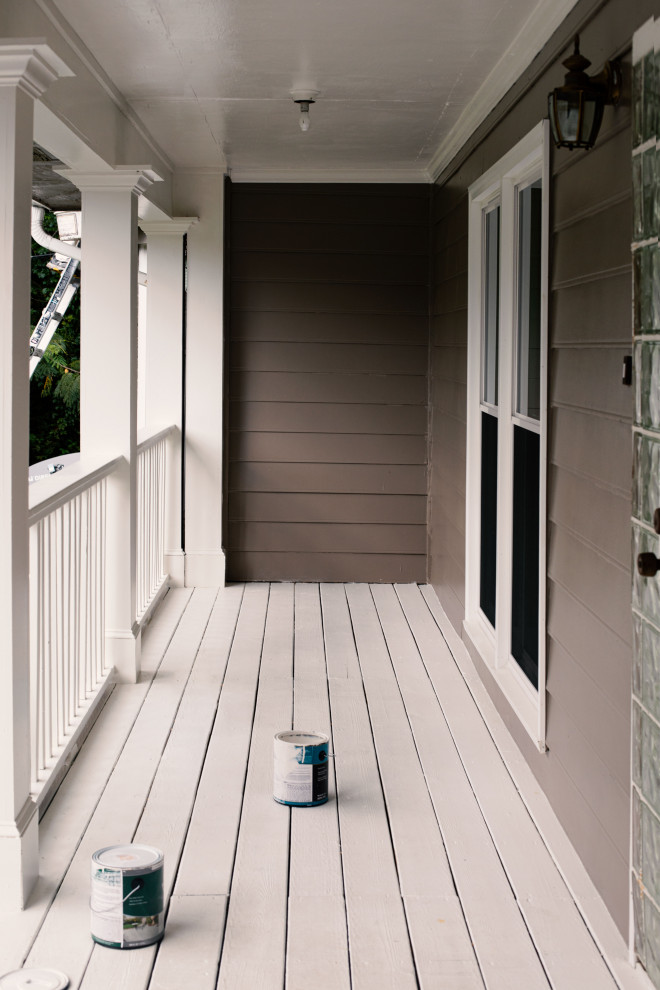Cette photo montre un porche d'entrée de maison avant chic de taille moyenne avec des colonnes et un garde-corps en bois.