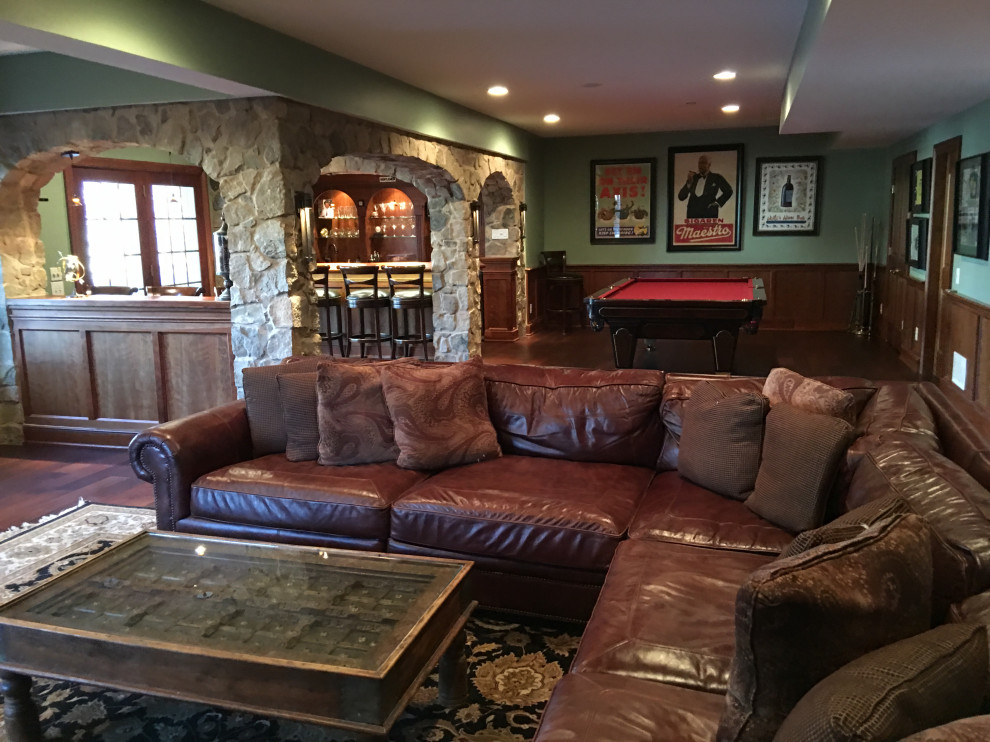 Photo of a large traditional walk-out basement in Philadelphia with green walls, dark hardwood floors, a standard fireplace, a stone fireplace surround and brown floor.