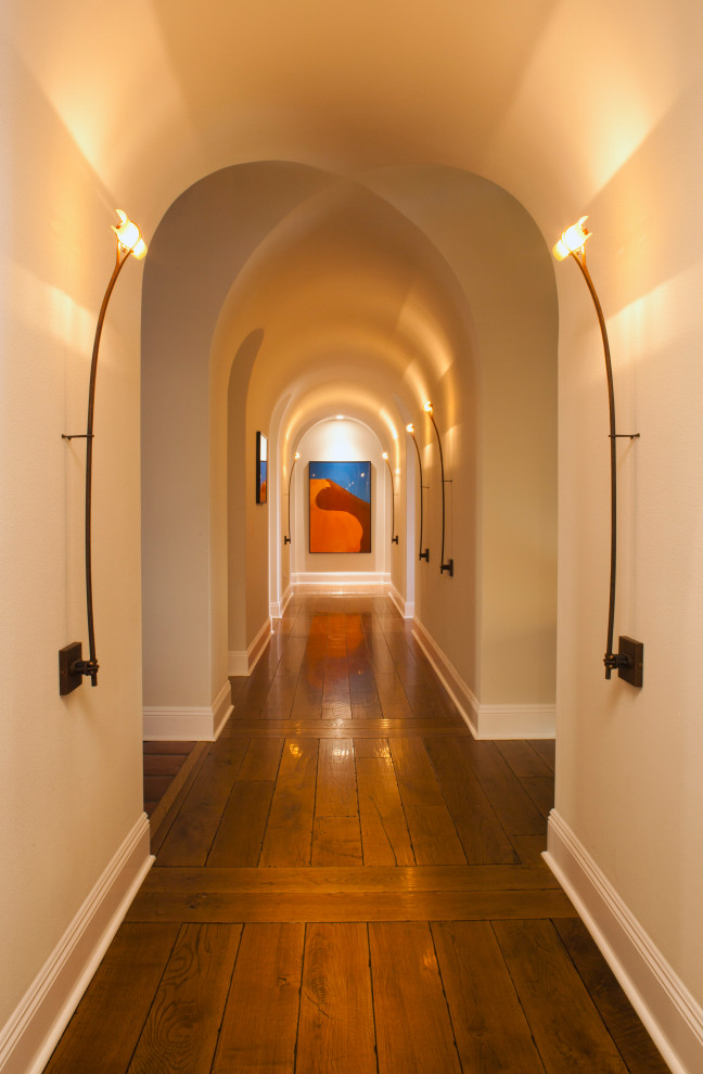 На фото: огромный коридор в средиземноморском стиле с бежевыми стенами, паркетным полом среднего тона, коричневым полом и сводчатым потолком