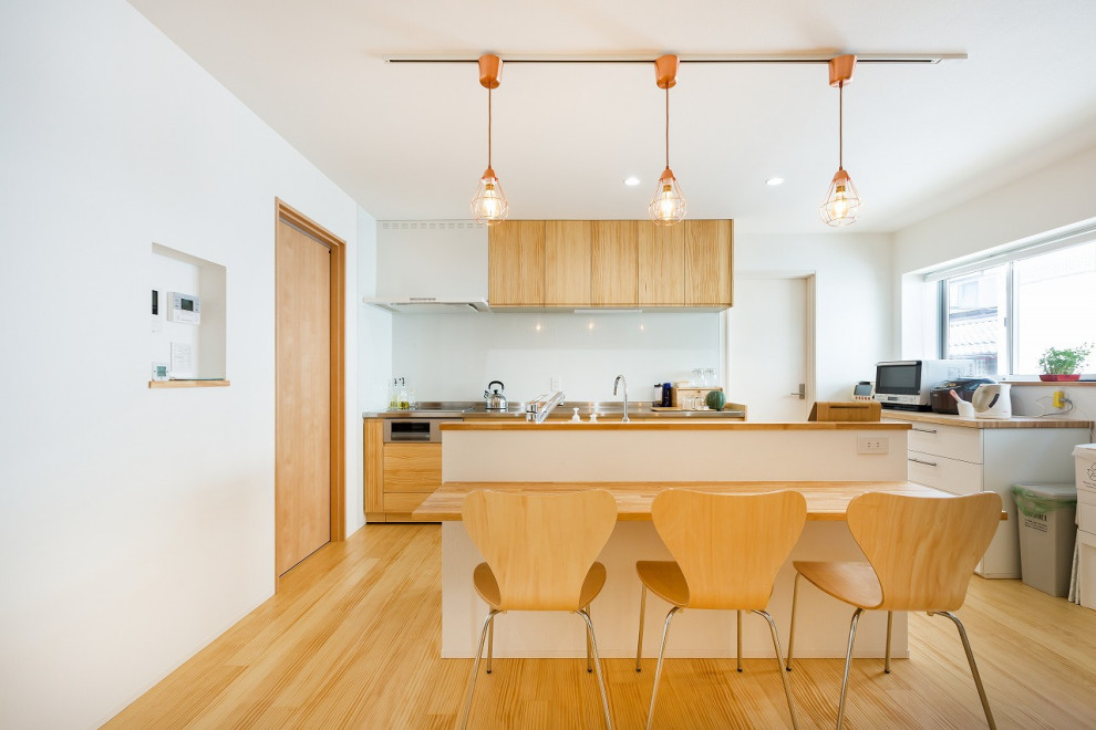 Photo of a mid-sized asian u-shaped kitchen in Other with flat-panel cabinets, white cabinets, wood benchtops, glass sheet splashback, with island, beige floor and brown benchtop.