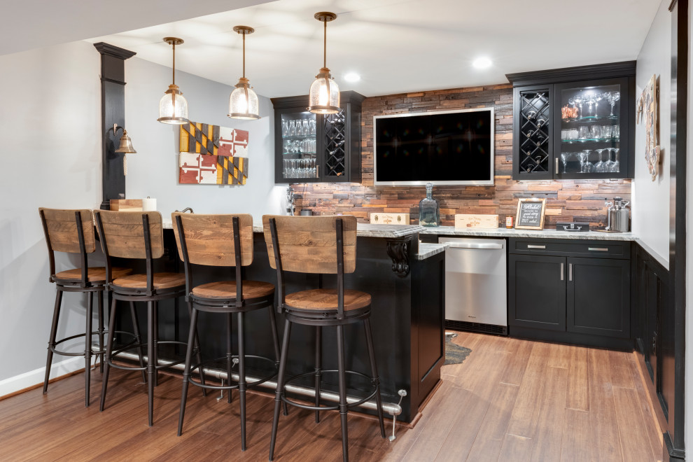 This is an example of a mid-sized traditional u-shaped wet bar in Baltimore with an undermount sink, shaker cabinets, black cabinets, granite benchtops, brown splashback, timber splashback, medium hardwood floors and white benchtop.
