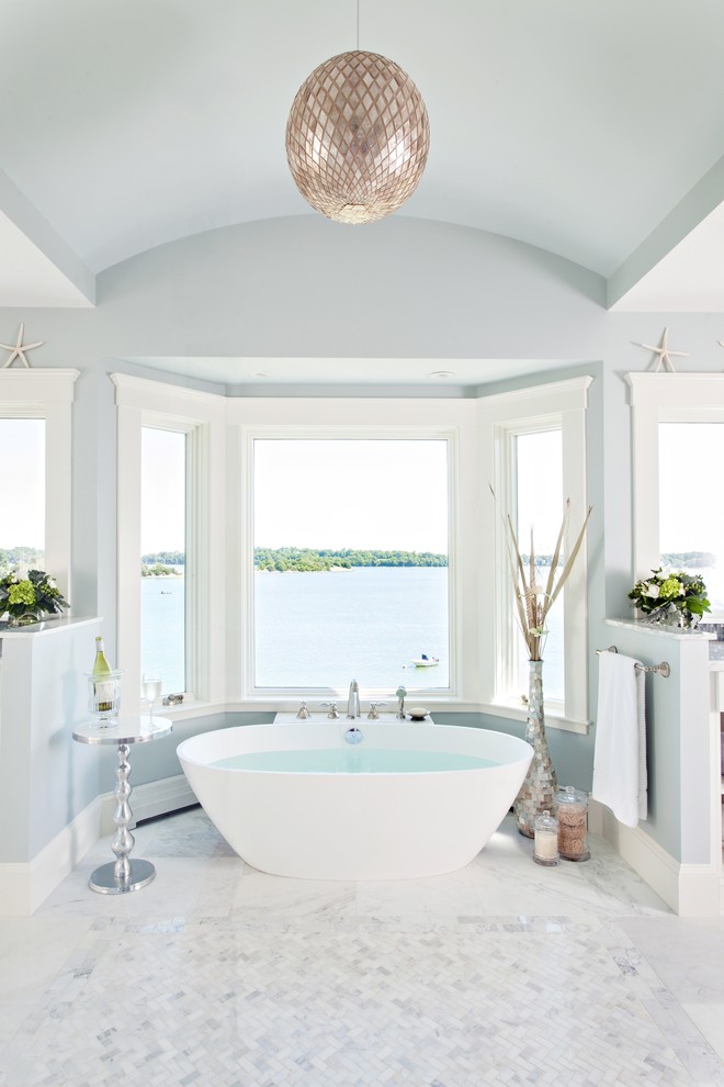 This is an example of a beach style master bathroom in Boston with a freestanding tub, mosaic tile, blue walls and white tile.