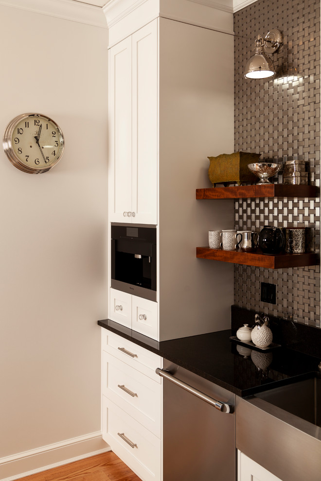 Enclosed kitchen - mid-sized transitional l-shaped enclosed kitchen idea with shaker cabinets, white cabinets, stainless steel appliances, an island and black countertops