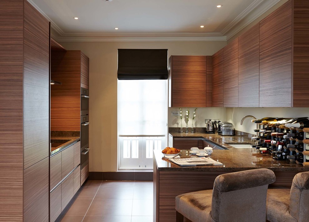 Photo of a large contemporary galley kitchen in London with an undermount sink, flat-panel cabinets, medium wood cabinets, granite benchtops, stainless steel appliances and a peninsula.