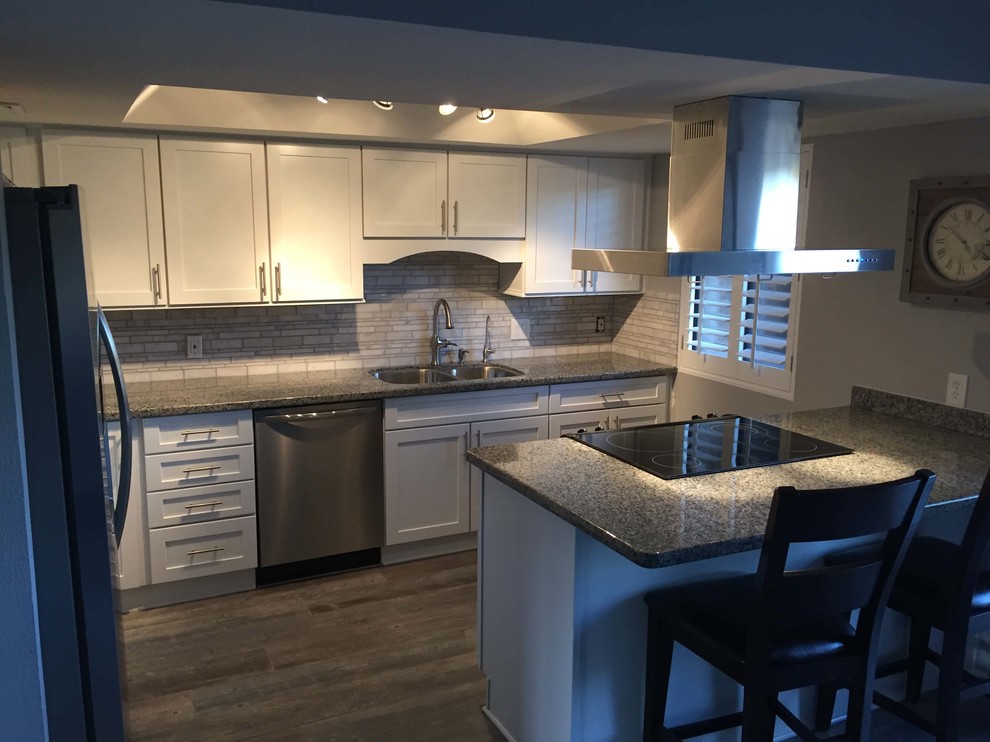 Example of a mid-sized transitional u-shaped dark wood floor eat-in kitchen design with a double-bowl sink, raised-panel cabinets, dark wood cabinets, wood countertops, gray backsplash, subway tile backsplash, white appliances and no island
