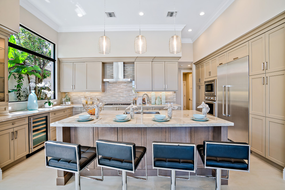 Inspiration for a transitional u-shaped kitchen in Miami with an undermount sink, beige cabinets, beige splashback, matchstick tile splashback, stainless steel appliances, with island, beige floor, grey benchtop and recessed-panel cabinets.