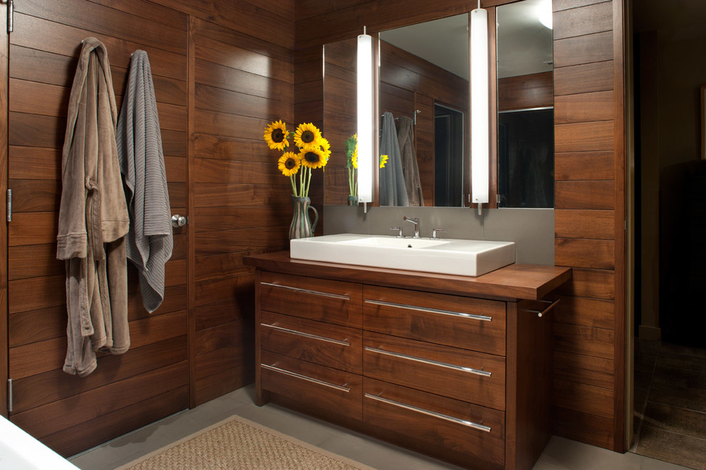 Photo of a mid-sized midcentury master bathroom in Other with flat-panel cabinets, dark wood cabinets, wood benchtops, brown walls, ceramic floors, a vessel sink and grey floor.