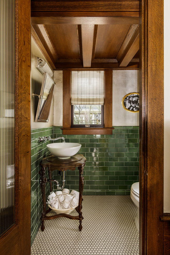 Photo of a mid-sized traditional powder room in Portland with dark wood cabinets, multi-coloured walls, a vessel sink, white floor, furniture-like cabinets, green tile, mosaic tile floors, wood benchtops, brown benchtops, a one-piece toilet, porcelain tile, a freestanding vanity and coffered.