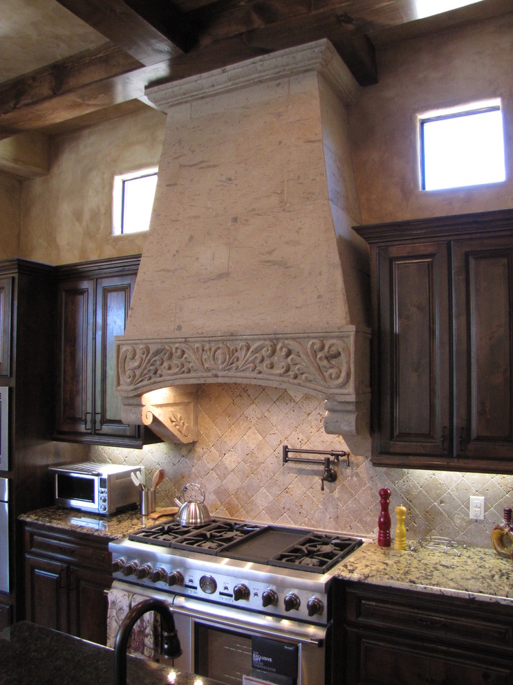 Design ideas for a large mediterranean l-shaped open plan kitchen in Austin with raised-panel cabinets, granite benchtops, stone tile splashback, stainless steel appliances, travertine floors and multiple islands.