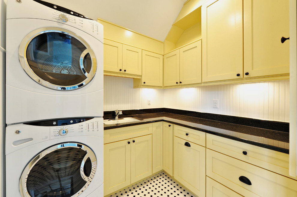 This is an example of a traditional laundry room in Philadelphia with a stacked washer and dryer and multi-coloured floor.