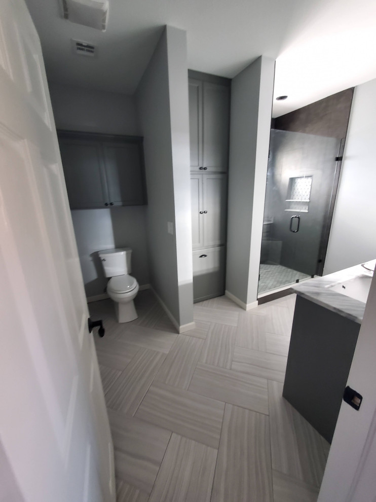 This is an example of a medium sized contemporary ensuite bathroom in Other with a two-piece toilet, grey walls, cement flooring, grey floors, a wall niche, wallpapered walls, beaded cabinets, white cabinets, a corner shower, grey tiles, a built-in sink, engineered stone worktops, a hinged door, multi-coloured worktops, double sinks, a built in vanity unit and a wallpapered ceiling.