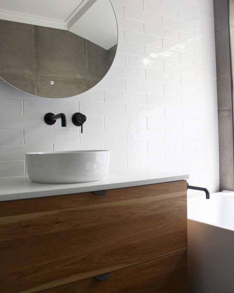 Inspiration for a small modern 3/4 bathroom in Perth with flat-panel cabinets, dark wood cabinets, a freestanding tub, a corner shower, white tile, ceramic tile, white walls, porcelain floors, a vessel sink, engineered quartz benchtops, grey floor, a hinged shower door and white benchtops.