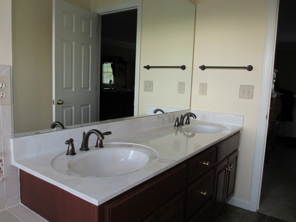 This is an example of a mid-sized traditional master bathroom in Other with an integrated sink, raised-panel cabinets, medium wood cabinets, laminate benchtops, a corner tub, an alcove shower, a one-piece toilet, beige tile, porcelain tile, beige walls and linoleum floors.