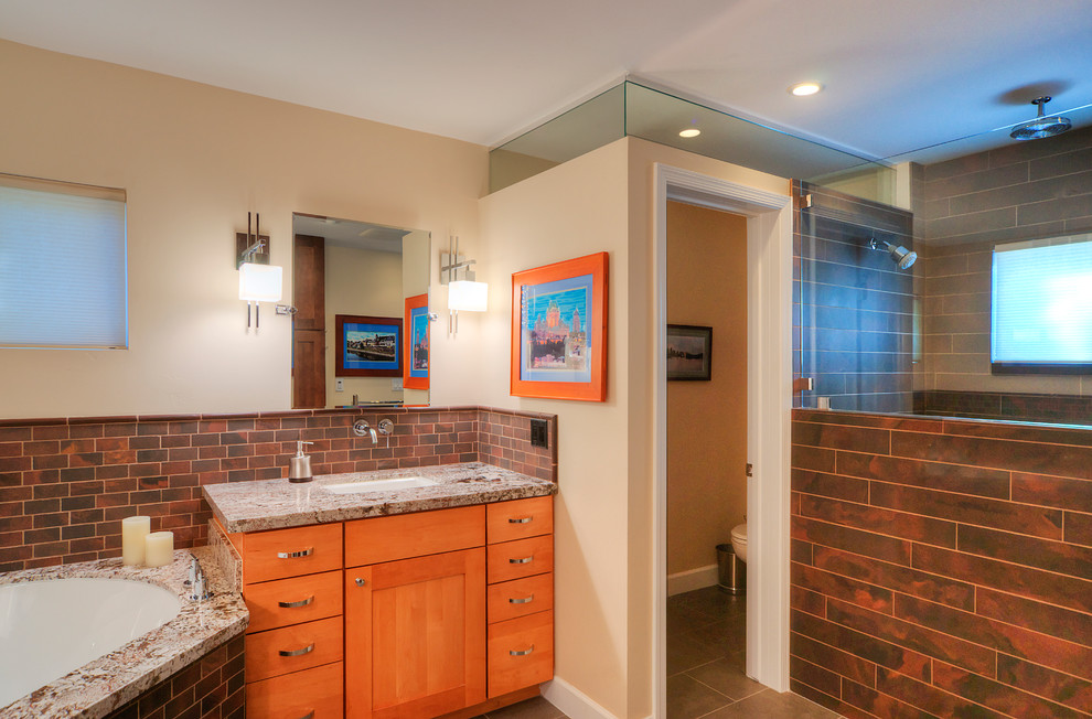 This is an example of a large eclectic master bathroom in Phoenix with shaker cabinets, light wood cabinets, a corner tub, a corner shower, brown tile, subway tile, beige walls, an undermount sink, granite benchtops, brown floor and grey benchtops.