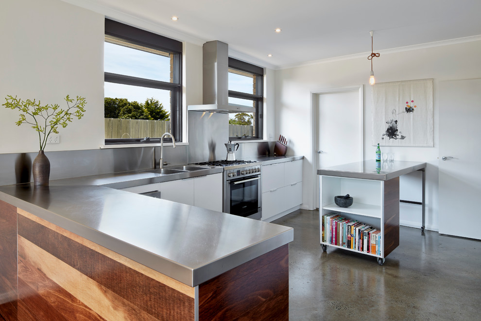 Design ideas for a mid-sized contemporary galley eat-in kitchen in Melbourne with an integrated sink, flat-panel cabinets, medium wood cabinets, stainless steel benchtops, stainless steel appliances, white walls, concrete floors and with island.