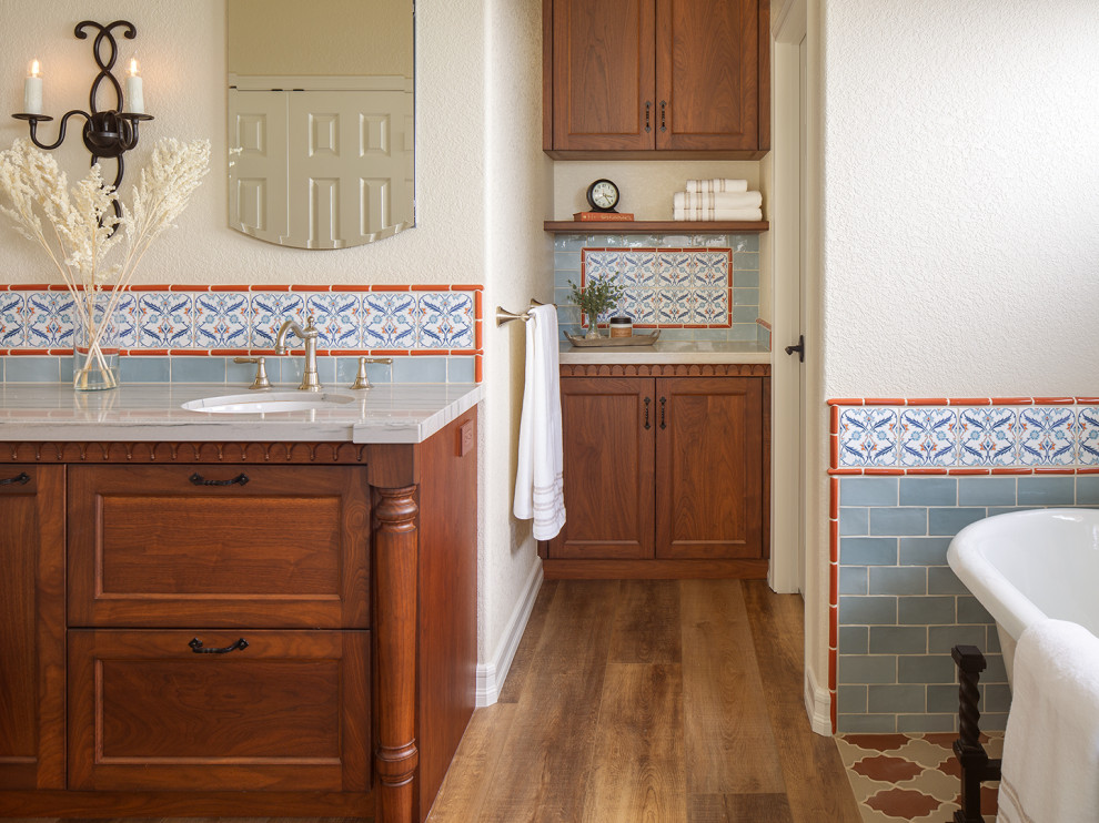На фото: большая главная ванная комната в средиземноморском стиле с плоскими фасадами, темными деревянными фасадами, отдельно стоящей ванной, душем в нише, синей плиткой, столешницей из кварцита, тумбой под две раковины и встроенной тумбой