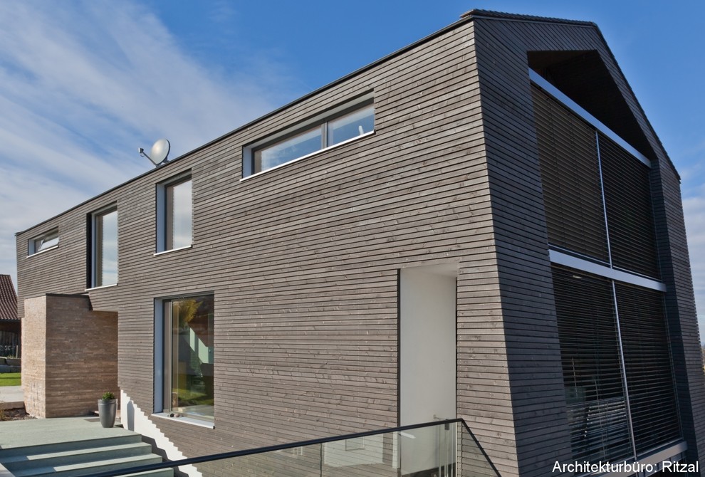 This is an example of a contemporary grey exterior in Stuttgart with wood siding.