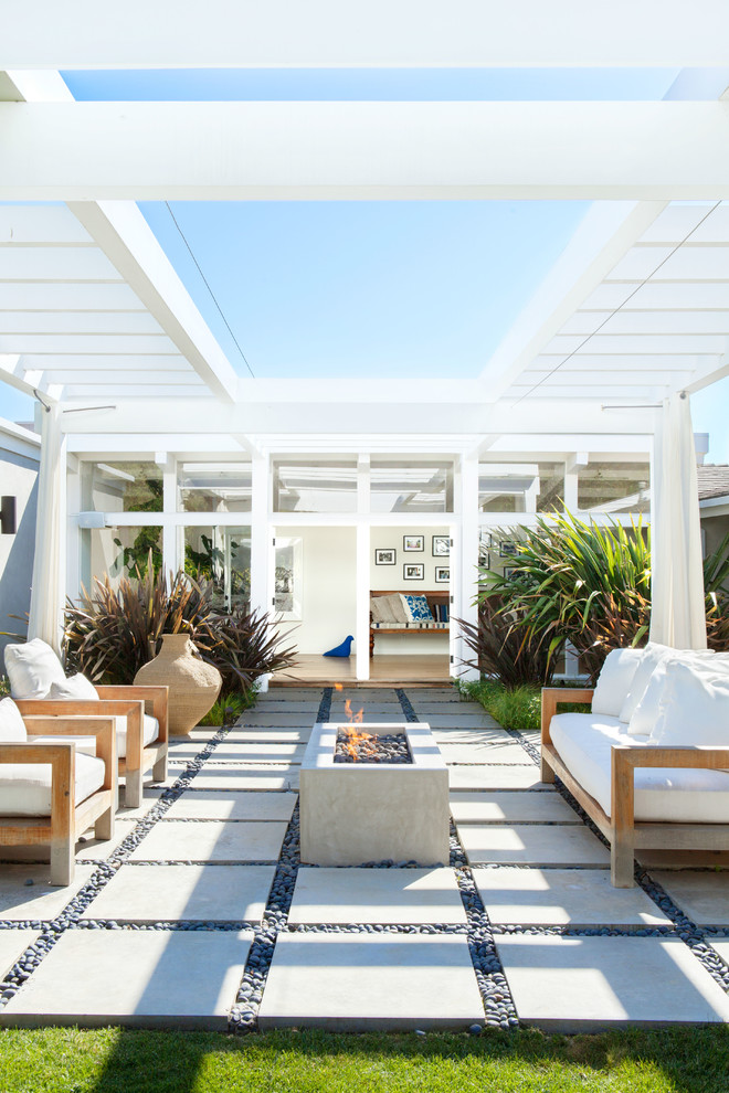 Photo of a contemporary backyard patio in Los Angeles with a fire feature, concrete pavers and a pergola.