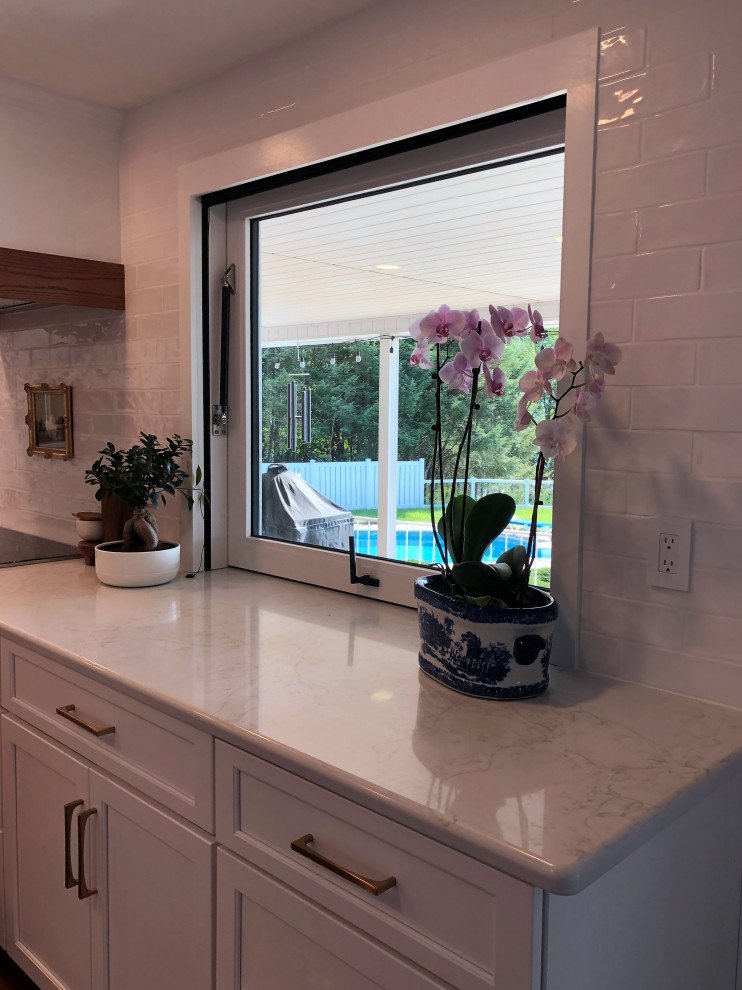 Example of a mid-sized transitional l-shaped medium tone wood floor and brown floor kitchen pantry design with an undermount sink, flat-panel cabinets, blue cabinets, quartz countertops, white backsplash, subway tile backsplash, stainless steel appliances, an island and gray countertops
