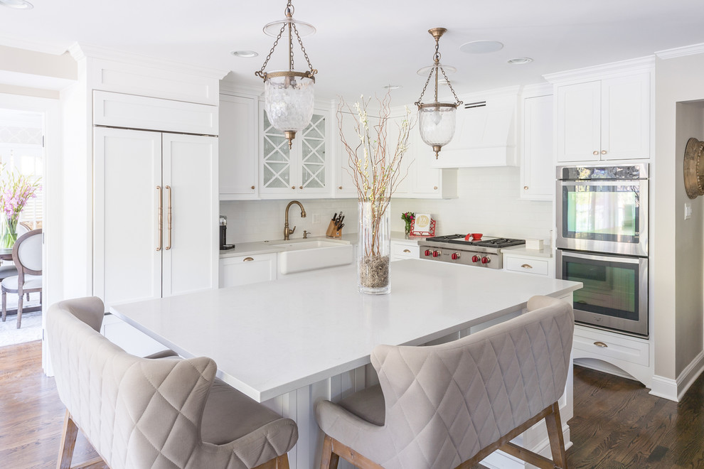 Inspiration for a large transitional l-shaped dark wood floor kitchen remodel in DC Metro with a farmhouse sink, white cabinets, quartz countertops, white backsplash, ceramic backsplash, paneled appliances, an island and shaker cabinets