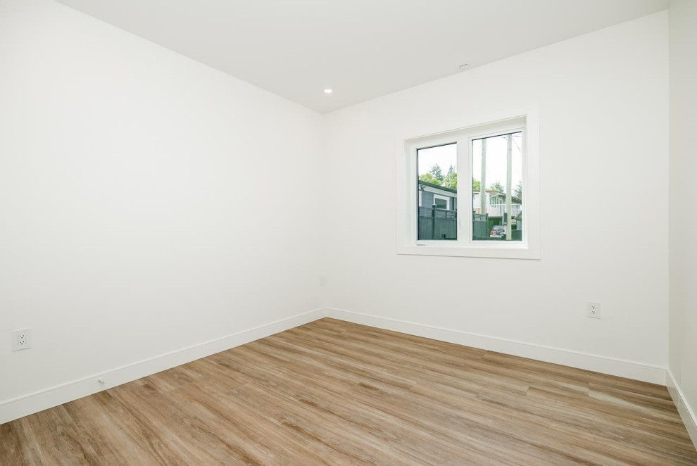 Inspiration for a mid-sized laminate floor and brown floor bedroom remodel in Vancouver with white walls and no fireplace