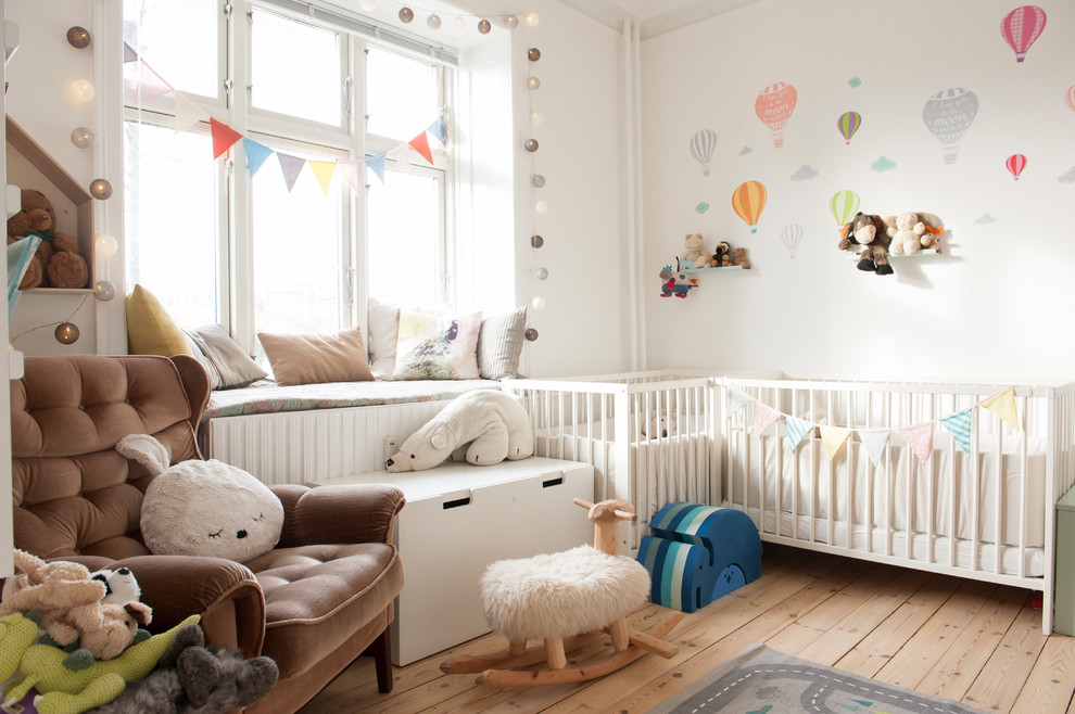 Inspiration for a scandinavian gender-neutral nursery in Los Angeles with white walls, medium hardwood floors and brown floor.