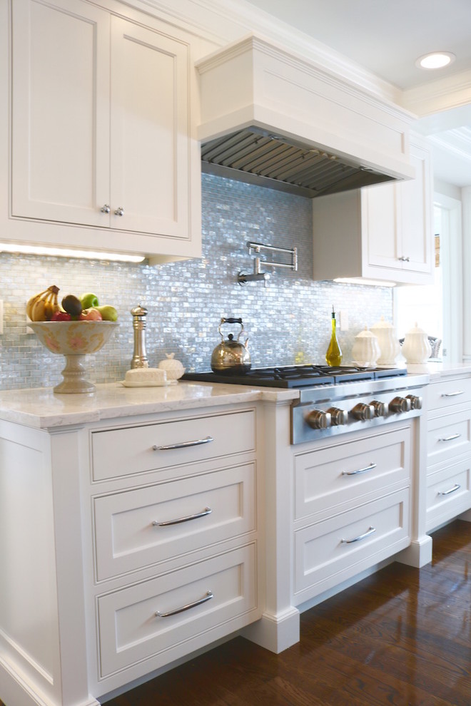 Design ideas for a large traditional u-shaped eat-in kitchen in Boston with a farmhouse sink, beaded inset cabinets, white cabinets, quartzite benchtops, blue splashback, glass tile splashback, white appliances, dark hardwood floors and with island.