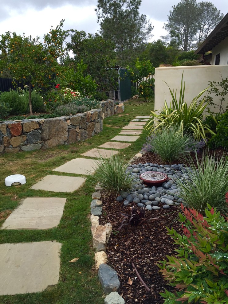 This is an example of an expansive contemporary side yard full sun xeriscape in San Diego with a garden path and natural stone pavers.