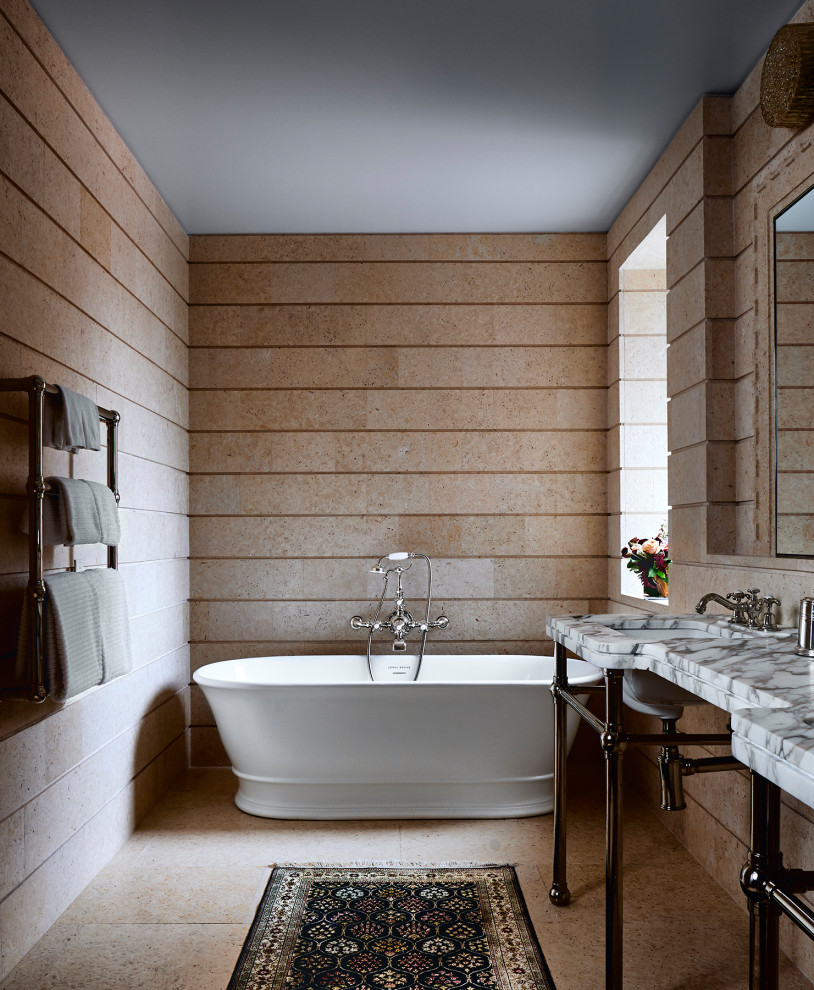 Photo of a mid-sized eclectic master bathroom in New York with a freestanding tub, a shower/bathtub combo, travertine, beige walls, travertine floors, a pedestal sink, marble benchtops, beige floor, multi-coloured benchtops, a double vanity and a freestanding vanity.