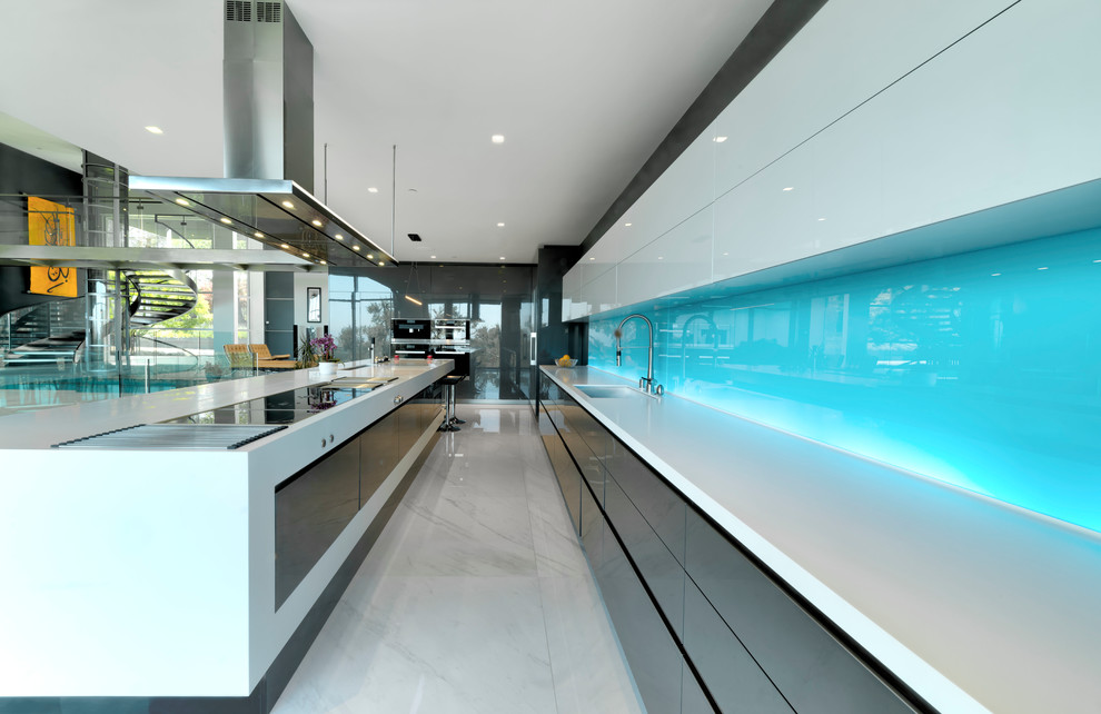 Inspiration for an expansive contemporary l-shaped eat-in kitchen in Nice with flat-panel cabinets, grey cabinets, solid surface benchtops, blue splashback, stainless steel appliances, porcelain floors, with island, white floor, white benchtop, an undermount sink and glass sheet splashback.