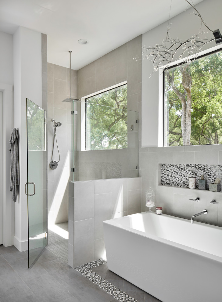 Example of a transitional master gray tile gray floor freestanding bathtub design with white walls and a hinged shower door