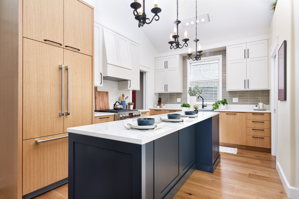 Mid-sized trendy l-shaped light wood floor and vaulted ceiling eat-in kitchen photo in Vancouver with a farmhouse sink, flat-panel cabinets, light wood cabinets, quartzite countertops, green backsplash, ceramic backsplash, stainless steel appliances, an island and white countertops