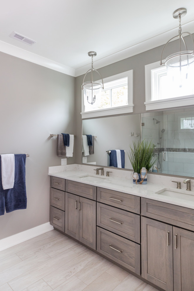 This is an example of a large beach style master bathroom in Milwaukee with flat-panel cabinets, medium wood cabinets, beige tile, porcelain tile, beige walls, porcelain floors, an undermount sink, engineered quartz benchtops, beige floor, a hinged shower door, white benchtops, an enclosed toilet, a double vanity and a built-in vanity.