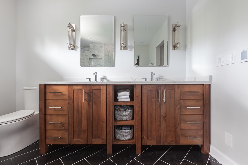 Mid-sized scandinavian master bathroom in Chicago with shaker cabinets, medium wood cabinets, a freestanding tub, a corner shower, a one-piece toilet, gray tile, marble, grey walls, travertine floors, an undermount sink, engineered quartz benchtops, black floor and a hinged shower door.