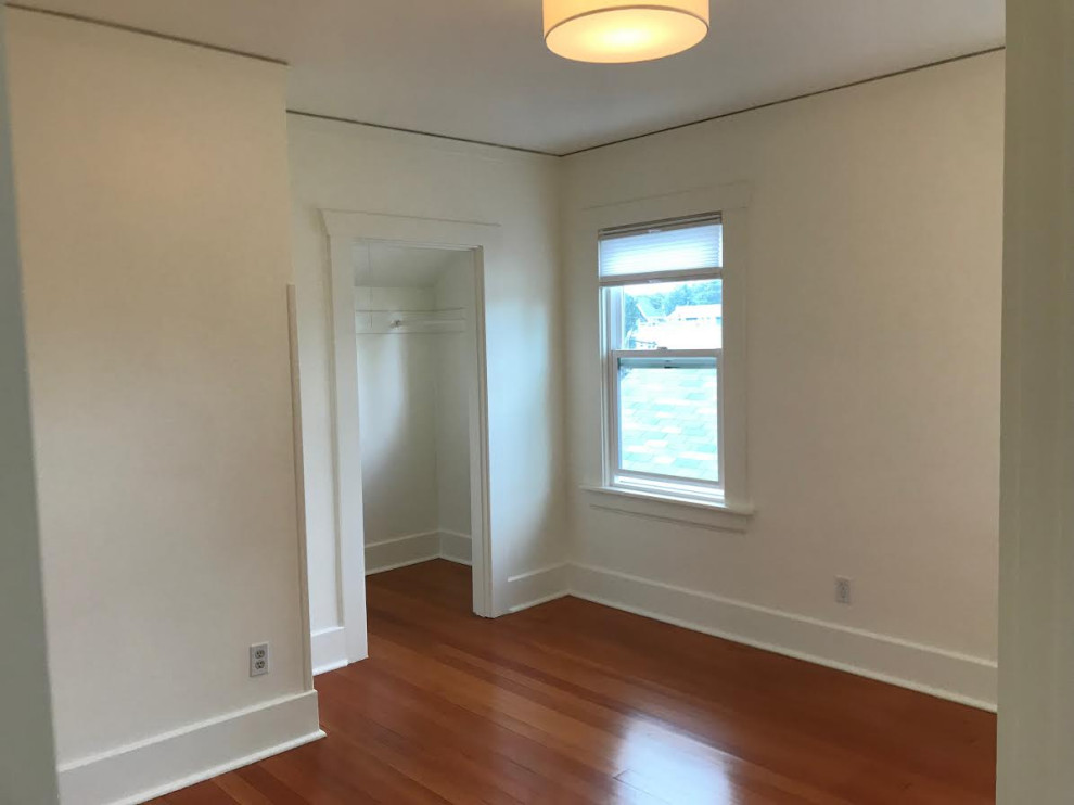 Photo of a mid-sized arts and crafts guest bedroom in Seattle with white walls, medium hardwood floors and red floor.