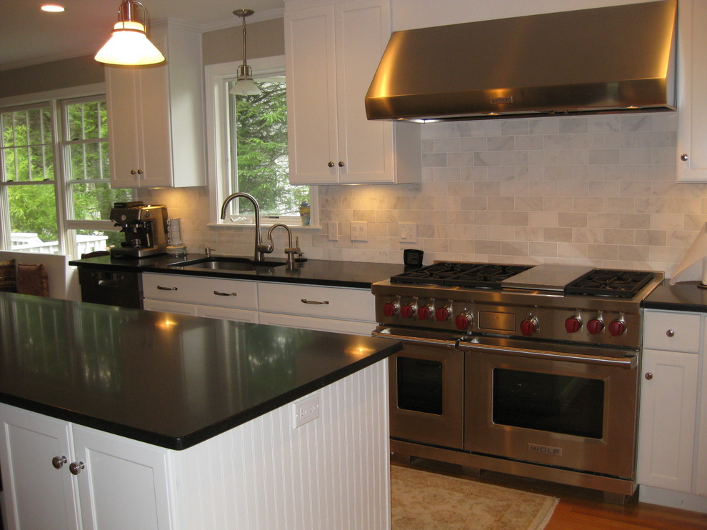 Eat-in kitchen - transitional u-shaped medium tone wood floor eat-in kitchen idea in Boston with an undermount sink, recessed-panel cabinets, white cabinets, gray backsplash, subway tile backsplash, stainless steel appliances, an island and black countertops