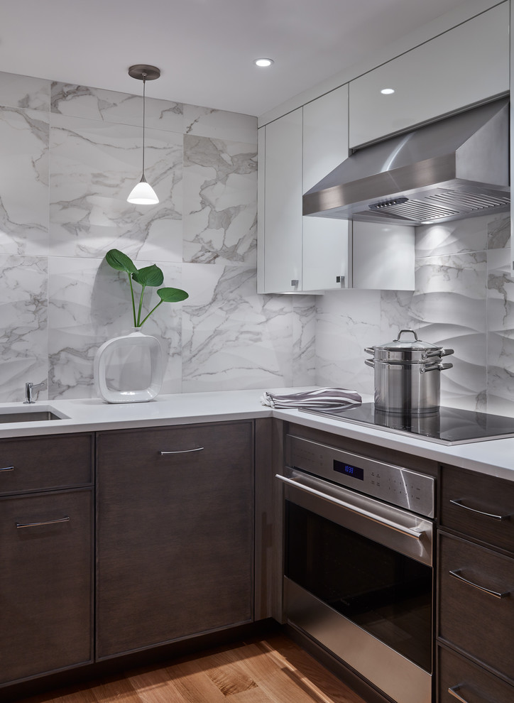 Photo of a small modern u-shaped separate kitchen in Boston with an undermount sink, flat-panel cabinets, dark wood cabinets, solid surface benchtops, white splashback, marble splashback, stainless steel appliances, light hardwood floors, no island, brown floor and white benchtop.