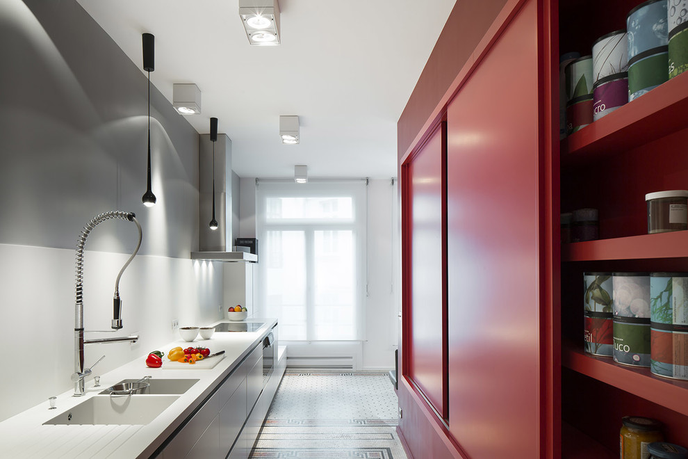 This is an example of a large contemporary single-wall separate kitchen in Paris with an integrated sink, flat-panel cabinets, white cabinets, marble benchtops, white splashback, panelled appliances and marble floors.