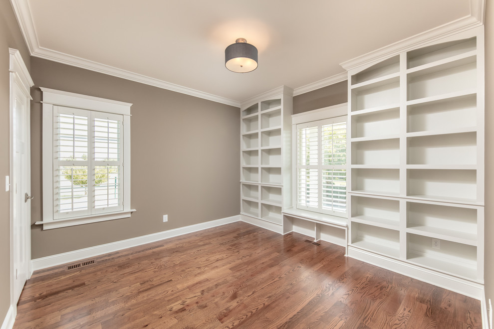 Photo of a large transitional home office in Other with a library, grey walls, dark hardwood floors, no fireplace and a freestanding desk.