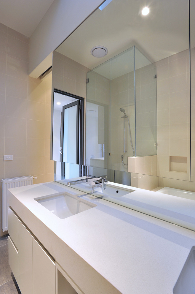 Inspiration for a mid-sized contemporary 3/4 bathroom in Melbourne with an undermount sink, engineered quartz benchtops, a corner shower, beige tile, beige walls, flat-panel cabinets, white cabinets, a drop-in tub, a one-piece toilet, ceramic tile and ceramic floors.