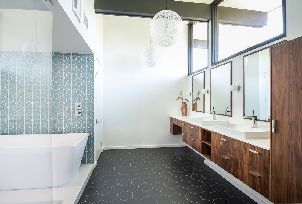 Inspiration for an expansive contemporary master wet room bathroom in Los Angeles with flat-panel cabinets, medium wood cabinets, a freestanding tub, blue tile, white walls, a vessel sink, black floor, an open shower, white benchtops, a double vanity and a floating vanity.