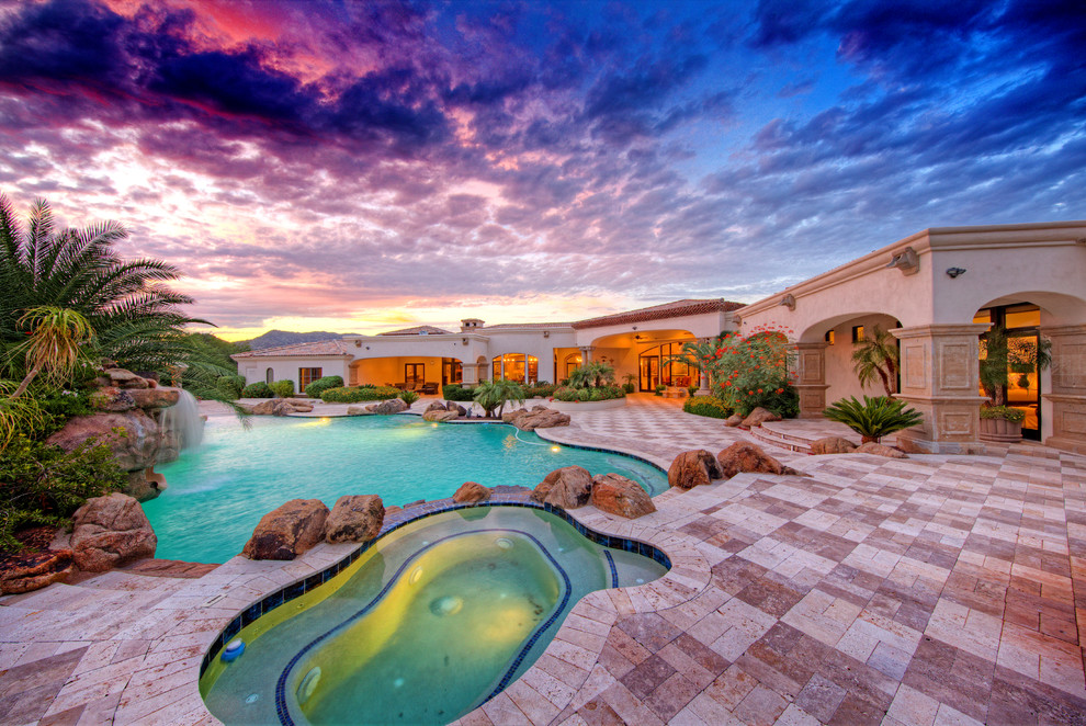 Expansive mediterranean backyard custom-shaped pool in Phoenix with brick pavers.